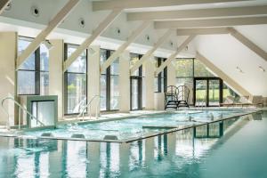 an indoor swimming pool with water in a building with windows at Thalazur Carnac in Carnac