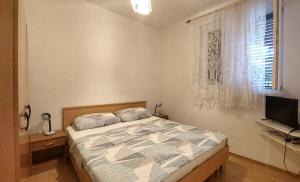 a bedroom with a bed and a television and a window at Apartments Dara in Umag