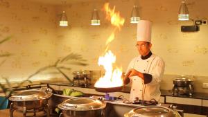 a chef is lighting a fire in a kitchen at SKYLAR Tirupati in Tirupati
