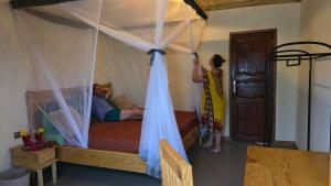 a man and a boy standing in a bedroom with a bed at JAC Tropical Lodge - Bar, Restaurant, Piscine, Massages, Plage, Nature, Excursions - Ressourcement et paix dans un paradis naturel et de confort les pieds dans l'eau - Respirez, vous êtes chez JAC - Navettes privées Banjul Aéroport in Diana