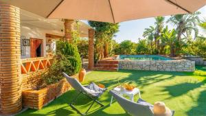 a backyard with a pool and two chairs and an umbrella at Villa Rocío, Acogedora villa con piscina de agua salada en Vélez Málaga in Almayate Alto
