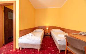 Interferie Chalkozyn w Kołobrzegu في كولوبرزيغ: سريرين في غرفة مع مكتب وطاولة +44 صورة