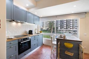 a kitchen with blue cabinets and a large window at Apartamento Davasa in Armação de Pêra