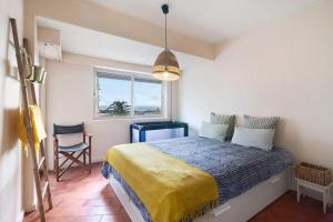 a bedroom with a bed and a window and a chair at Apartamento Davasa in Armação de Pêra