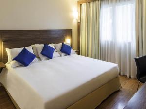 a large bed with blue pillows in a hotel room at Novotel Manaus in Manaus +177 photos
