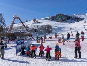 LE CORBIER Vue pistes Studio 5 personnes entièrement rénové في Villarembert: مجموعة من الأطفال على دراجات في الثلج