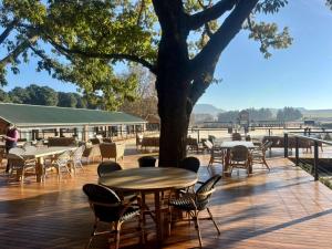 a wooden deck with tables and chairs and a tree at Waterwoods Equestrian Venue and Cottages in Nottingham Road