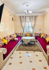 a living room with purple couches and a table at Jolie appartement calme avec cheminée & bois in Ifrane