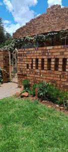 a brick wall next to a yard with grass at Bushman Spoor Backpackers in Soweto