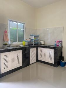 a kitchen with white cabinets and a sink and a window at Kubu home stay in Ban Ko Sawat