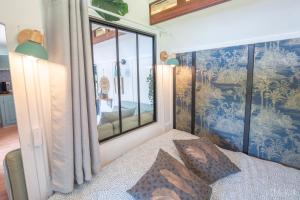 a bedroom with a bed with a large window at Roulotte avec bain nordique privatif chauffé, Séjour calme et bien-être in Fichous-Riumayou