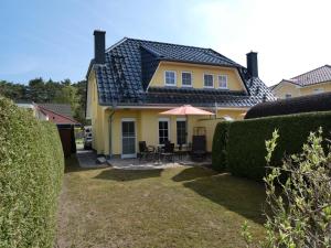een geel huis met een tafel en een paraplu bij Ferienhaus am Eikboom - DHH2 mit Fasssauna in Ostseebad Karlshagen