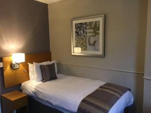 a hotel room with a bed and a picture on the wall at The George Inn in Selby +129 photos