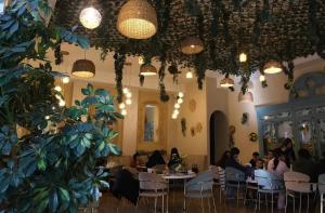 a group of people sitting at tables in a room with plants at Old Town Hostel Gyumri in Gyumri