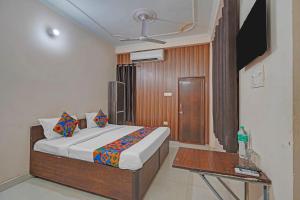 FabHotel Hare Rama في Prayagraj: غرفة نوم بها سرير وتلفزيون