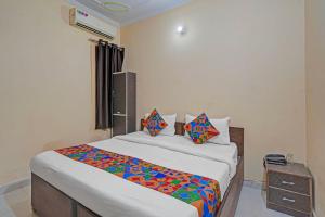 FabHotel Hare Rama في Prayagraj: غرفة نوم مع سرير مع أوراق ووسائد ملونة