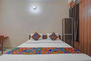 FabHotel Hare Rama في Prayagraj: غرفة نوم مع سرير مع بطانية ملونة عليه