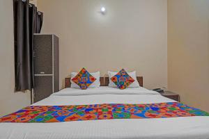 FabHotel Hare Rama في Prayagraj: سرير مع ملاءات ملونة ووسائد عليه +16 صورة