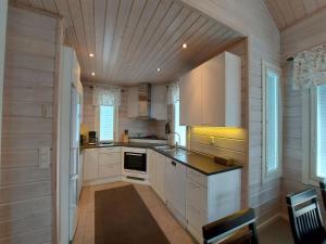 una cucina con mobili bianchi e soffitto in legno di Sunski a Syöte