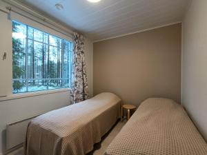 een slaapkamer met twee bedden en een raam bij Syötemaja in Pudasjärvi