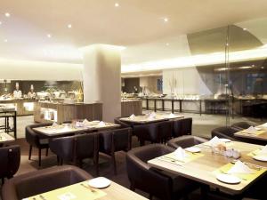 a restaurant with tables and chairs and a kitchen at Shenzhen Novotel Watergate in Shenzhen