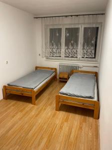 twee bedden in een kamer met houten vloeren en een raam bij Ubytovanie u Grófa in Turany