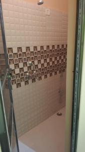 ein Bad mit einer Dusche und einer Fliesenwand in der Unterkunft Shri Ram Bhavan Homestay in Varanasi