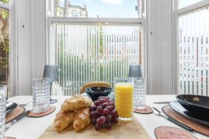 una mesa con un plato de comida y un vaso de jugo de naranja en Modern 2bed Flat 5 min walk to Brixton & Clapham, en Londres