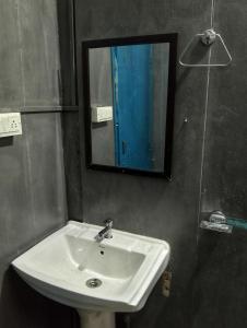 a bathroom with a white sink and a mirror at Ivan homestay in Kulu