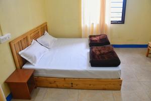 a bedroom with a wooden bed with white sheets and pillows at Ivan homestay in Kulu