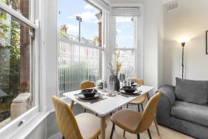 Un comedor con una mesa y sillas y un sofá. en Modern 2bed Flat 5 min walk to Brixton & Clapham, en Londres
