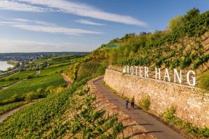 two people walking down a path next to a wall with a sign that saysnor at Ferienwohnungen Uhrturm in Oppenheim +8 photos