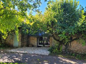 a brick building with a door under a tree at la maison du grand mas in Mouret