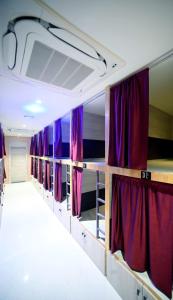 een rij stapelbedden met paarse gordijnen bij Umaa Sleeping Beds Dormitory in Pārvatīpuram