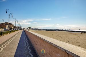 a sidewalk next to a beach with a wall and street lights at Dani's House in Isola Sacra