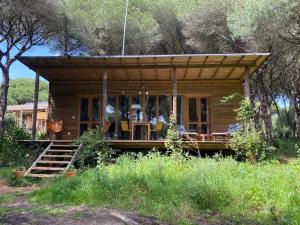 a small log cabin with a porch and chairs in the woods at miCielo - Baumhäuser in Vejer de la Frontera