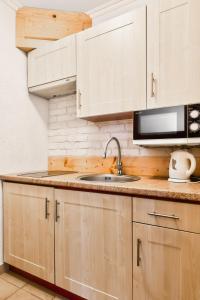 a kitchen with wooden cabinets and a sink and a microwave at Willa Vera Zakopane in Zakopane +76 photos