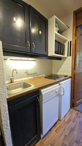 a kitchen with black cabinets and a white dishwasher at Val Thorens - Ski InOut - 4 Beds Flat C-E19 in Béranger