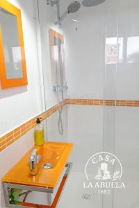 y baño con lavabo de color naranja y ducha. en Casa La Abuela 1982, en La Iruela