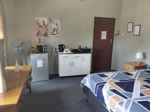a bedroom with a bed and a kitchen with a refrigerator at Germiston Residential Motel in Germiston