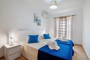 una camera con due letti con lenzuola blu e una finestra di Monte Fino Beach a Monte Gordo