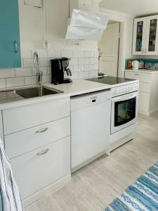 a white kitchen with a sink and a stove at Traditional Red House By The Lake In Småland in Åby