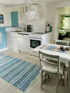 a kitchen with white appliances and a table with a rug at Traditional Red House By The Lake In Småland in Åby +32 photos