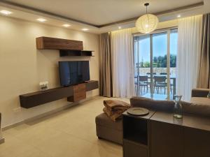 a living room with a couch and a television and a table at Veduta Ta Pinu Apartments with Stunning Views Garden Sauna Pool and Gym in Għarb