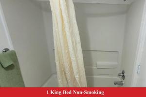 a bathroom with a white shower curtain next to a toilet at Coratel Inn and Suites By Jasper Anthony in Anthony +18 photos
