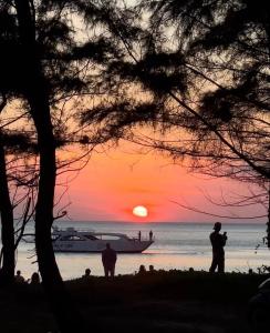 a group of people standing on the beach watching the sunset at Lanta Palm Beach Resort , Beach Bungalow - Koh Lanta in Ko Lanta