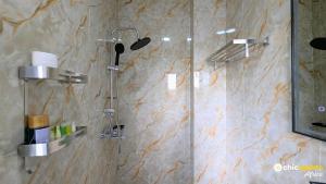 a shower with a glass door in a bathroom at Chic apart with parking and rooftop in Yaoundé +13 photos