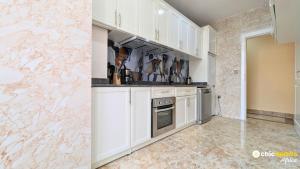 a kitchen with white cabinets and a marble wall at Chic apart with parking and rooftop in Yaoundé