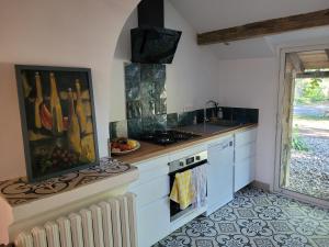 a kitchen with white cabinets and a sink and a stove at la maison du grand mas in Mouret