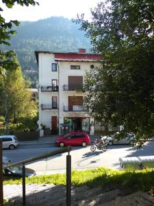 ein Gebäude mit einem roten Auto auf einem Parkplatz in der Unterkunft Central Greenlife in Tarvis